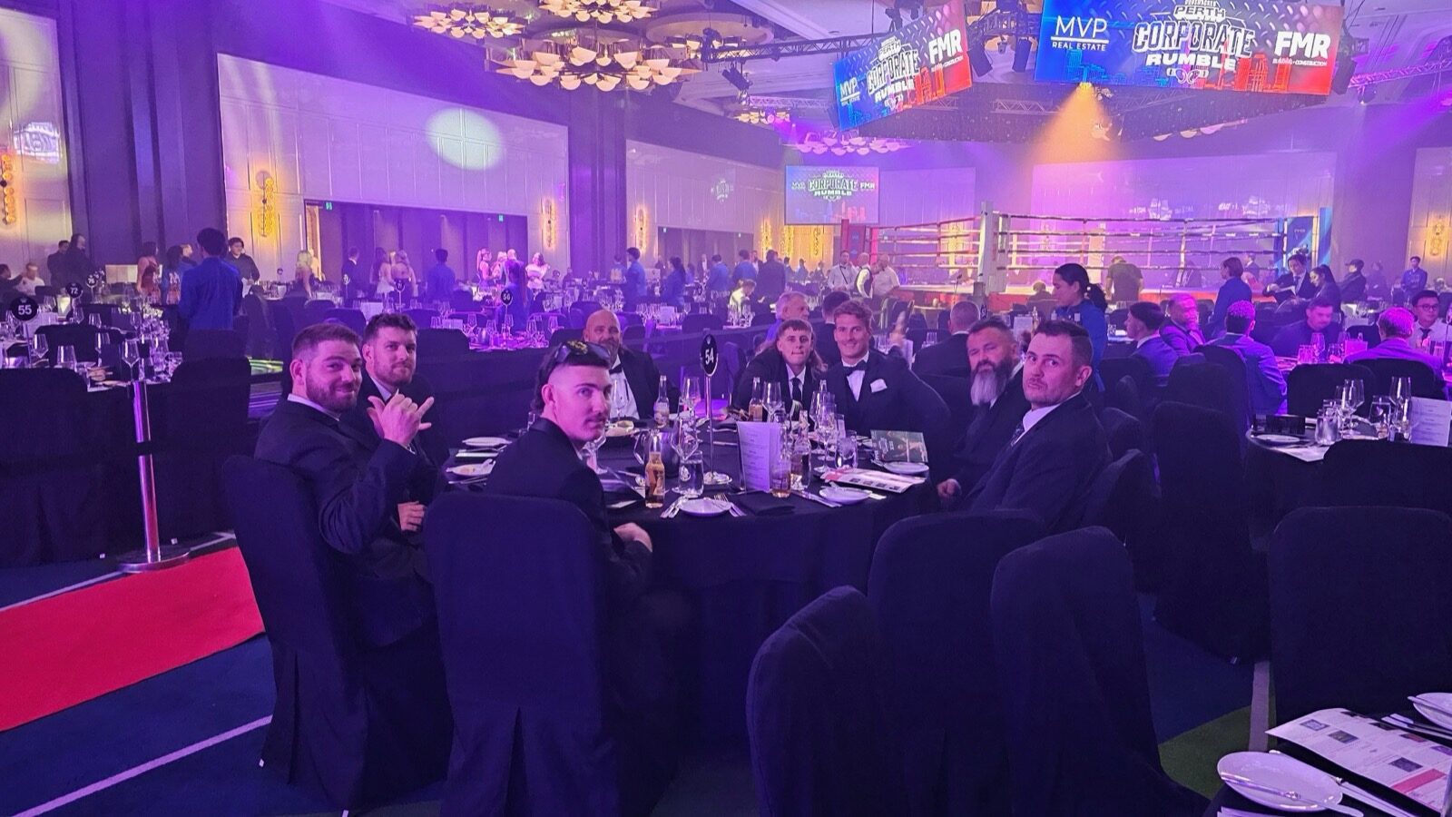 FMR team at their table with the boxing ring in the background